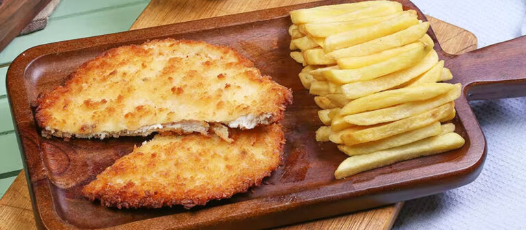 Ein rustikales Holztablett, das zwei goldbraun panierte Schnitzel und einen Stapel knuspriger Pommes Frites präsentiert.